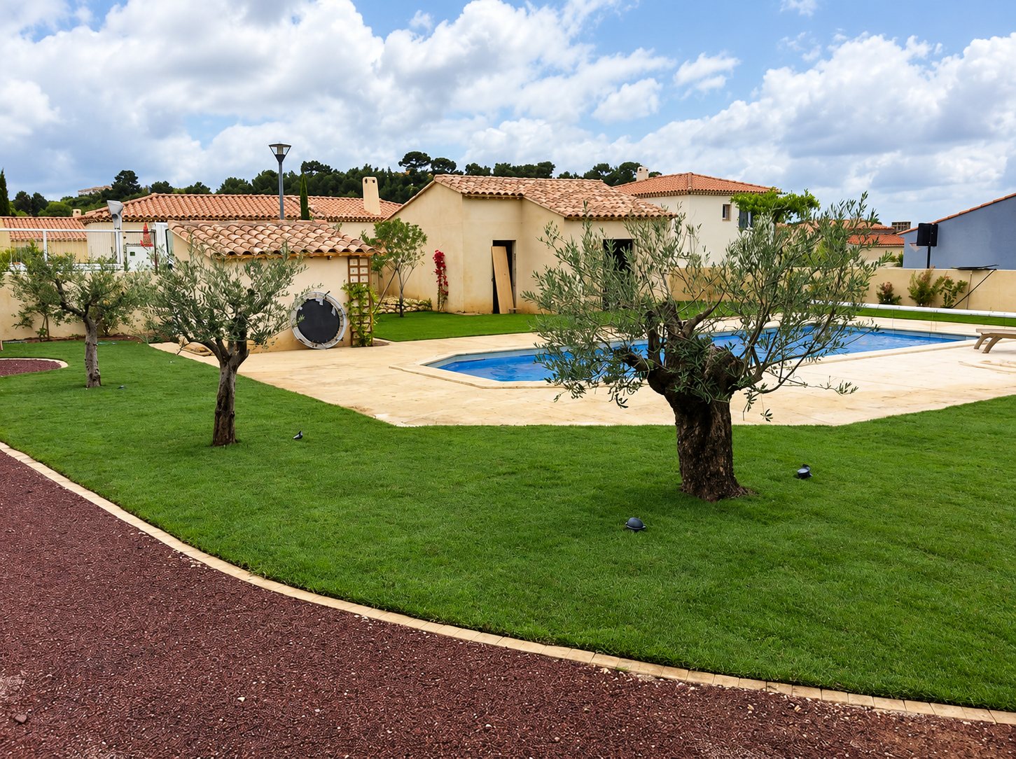 Jardin aménagé avec oliviers, pelouse neuve et piscine devant une villa provençale