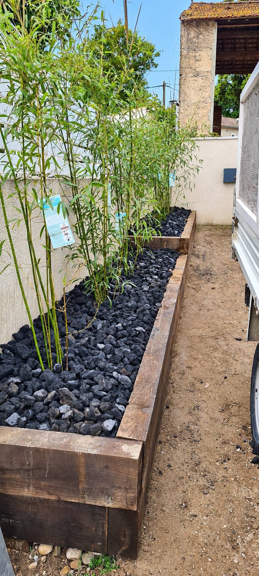 Jardinière en traverses de bois avec bambous et pouzzolane noire