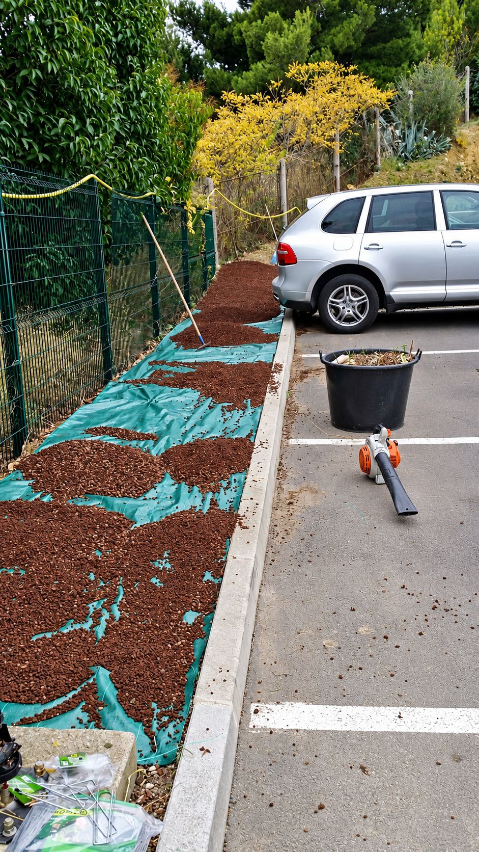 Paillage de pouzzolane rouge sur toile verte le long d'un parking