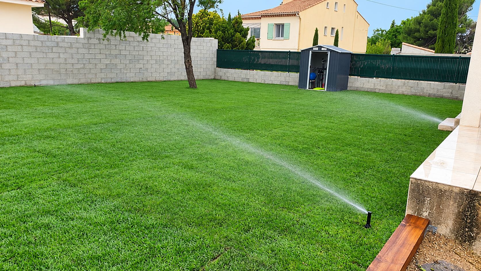Pelouse fraîchement posée arrosée par des arroseurs escamotables dans un jardin