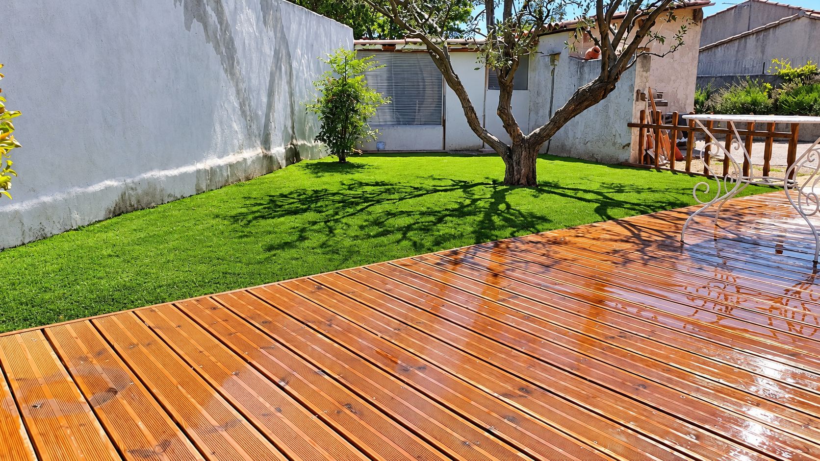 Terrasse en bois et pelouse synthétique dans un jardin ensoleillé